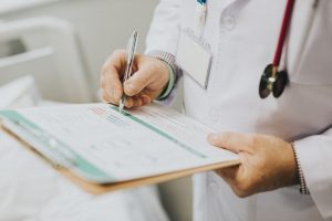 Physician noting down symptoms of a patient Physician noting down symptoms of a patient