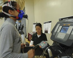 A woman researcher conducts a VO2 Max test on a patient. 