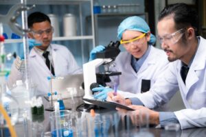 Three researchers, two men and a woman in a lab. The man in the foreground is recording findings. 