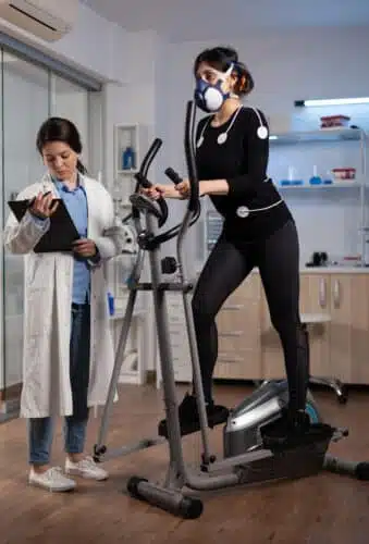 Researcher conducting a VO2 Max test on a patient on an elliptical machine. 