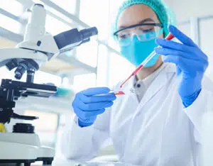 Female scientist performing blood test while working at a microscope in a laboratory.