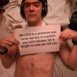 Eirik is holding a sign that reads: ME/CFS is a sentence you never earned, in a prison you can’t escape, for a length no one can tell you.