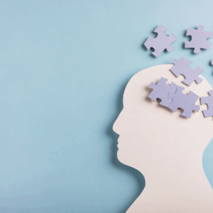 Silhouette of a human head on a blue background with puzzle pieces inside and floating away, symbolizing memory, thinking, or cognitive function.